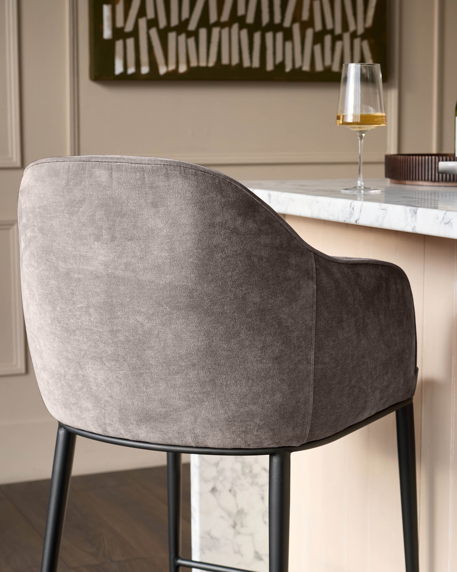Harley bar stool in mocha fabric, rear view showing curved backrest and black legs at marble countertop.