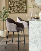 Mocha fabric bar stool with curved backrest and black metal legs, shown in styled room setting.