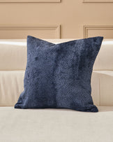 Navy textured cushion with a boucle weave, displayed on a cream upholstered sofa against a neutral wall.
