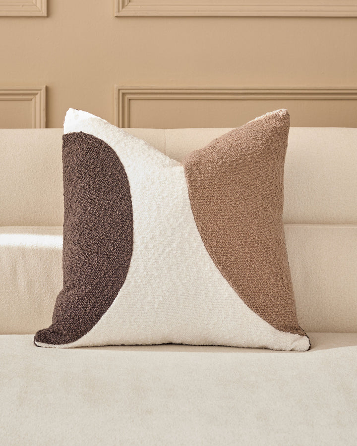 Harmony cushion in natural tones featuring a geometric wave pattern in cream, tan, and brown, displayed on a beige sofa.