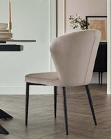 Harper dining chair in champagne velvet with black metal legs, shown from back angle in modern interior setting.