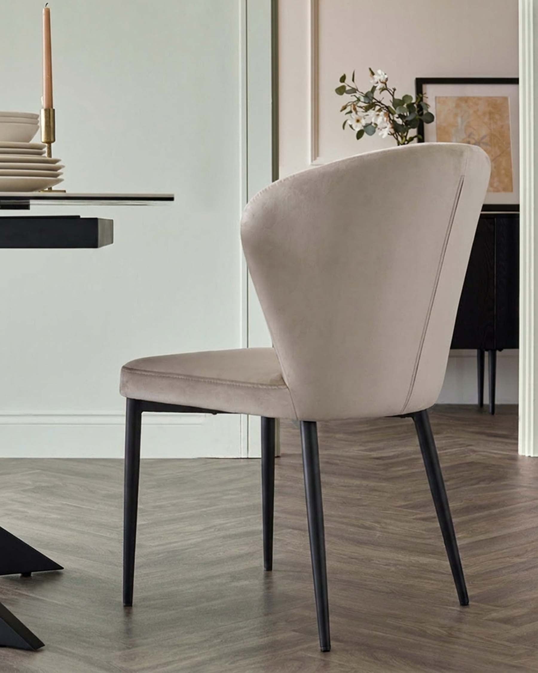 Harper dining chair in champagne velvet with black metal legs, shown from back angle in modern interior setting.