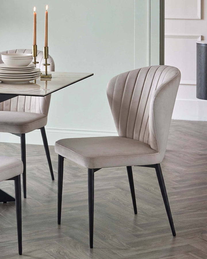 Harper dining chair in champagne velvet with black metal legs, shown in modern dining setting.
