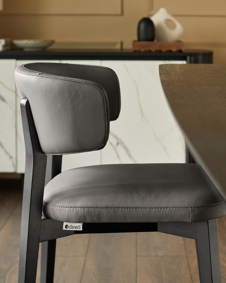 Close-up of a grey leather chair with a dark wooden frame, stylishly designed for comfort and modern living.