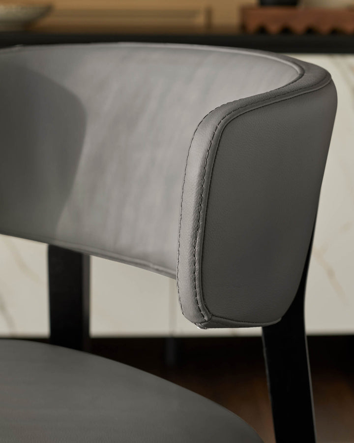 Close-up of a grey upholstered dining chair with a curved back, showcasing modern design and comfort.