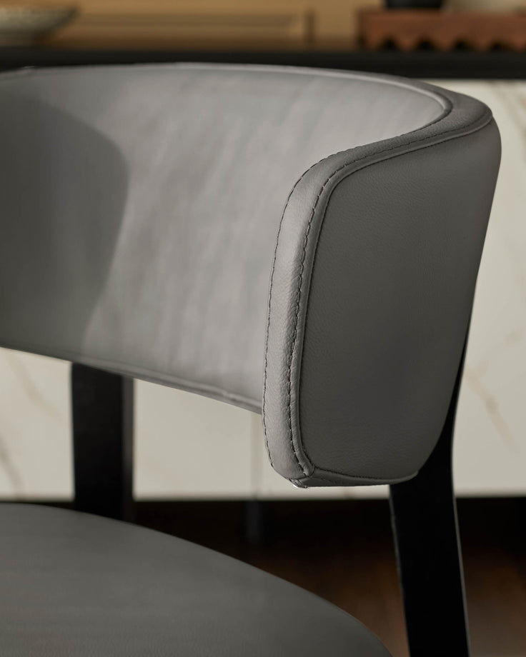 Close-up of a grey upholstered dining chair with a curved back, showcasing modern design and comfort.