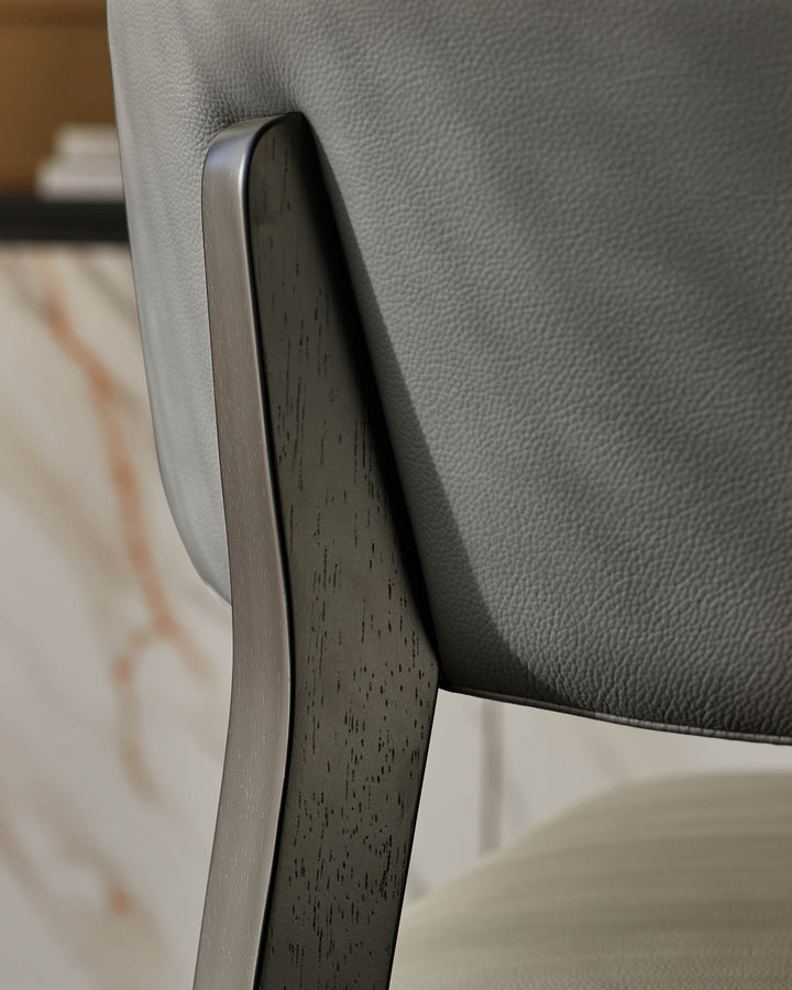 Close-up of a stylish grey leather chair with a dark wood frame. Modern design meets comfort.