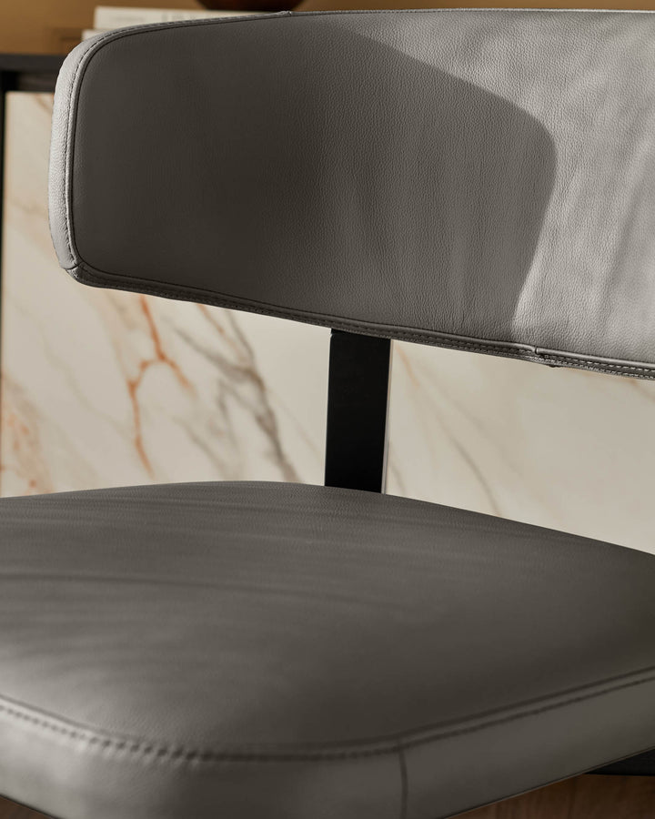 Close-up of a sleek, grey leather chair with a black frame, showcasing its minimalist design and quality craftsmanship.