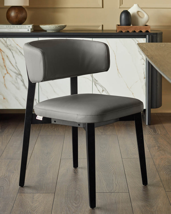 A grey leather dining chair with black legs sits on a wood floor in front of a marble sideboard.
