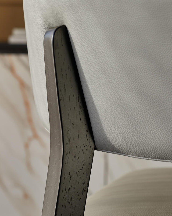 Close-up of a stylish, modern chair with light grey leather upholstery and a dark wood frame. Perfect for contemporary homes.