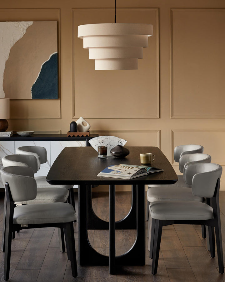 Dining room with wood table, light grey leather chairs, sideboard, and a tiered pendant light.