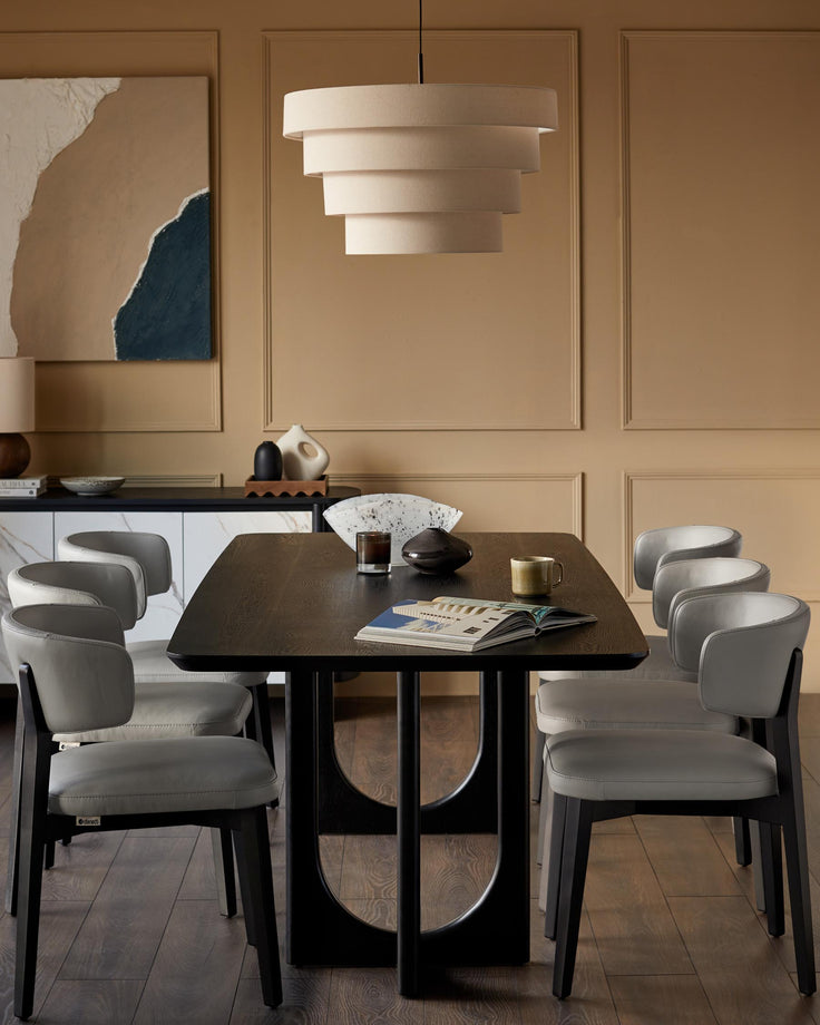 Dining room with wood table, light grey leather chairs, sideboard, and a tiered pendant light.
