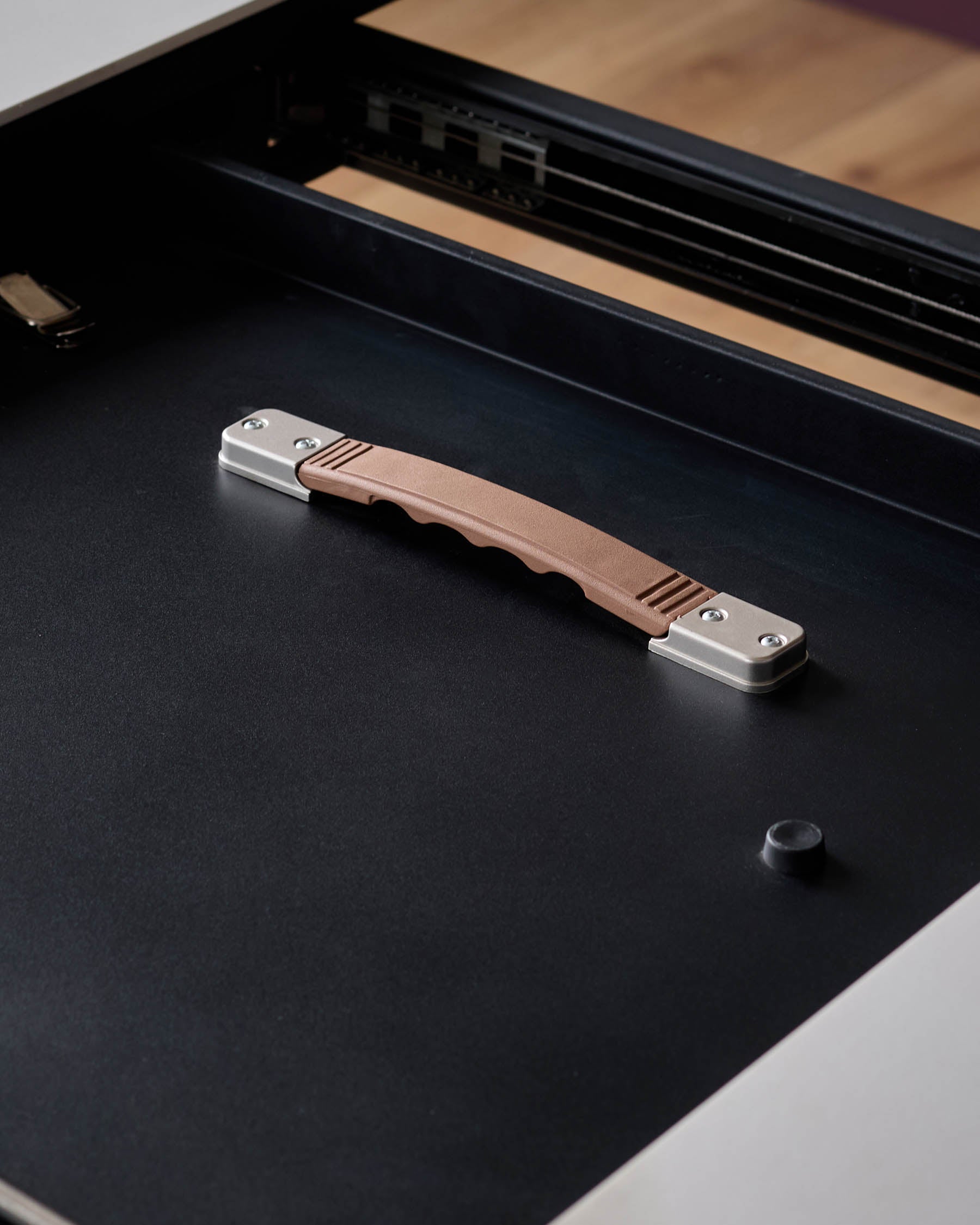 A black drawer with a brown and silver handle, showcasing a modern furniture design.