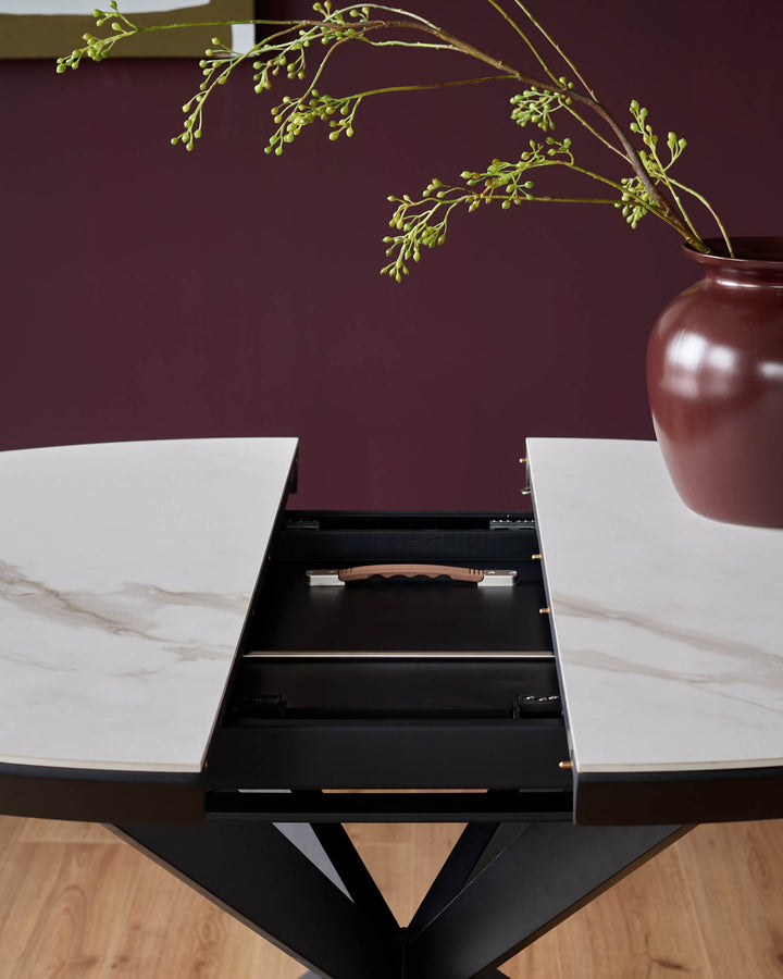 A modern, extendable dining table with a faux marble top and striking black base. A floral centrepiece adds a touch of elegance.