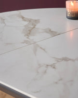 Marble effect extending dining table with a burning candle. Close up of surface. Elegant dining furniture.