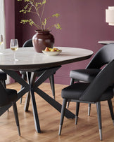 A round dining table with a marble effect top and black chairs with metal tipped legs are on display.