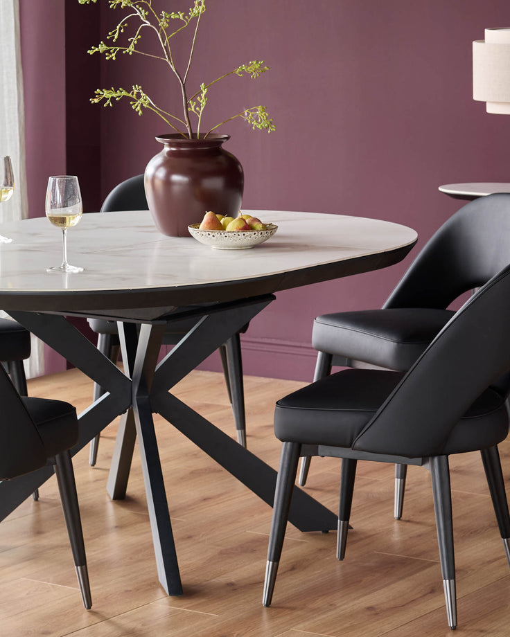 A round dining table with a marble effect top and black chairs with metal tipped legs are on display.