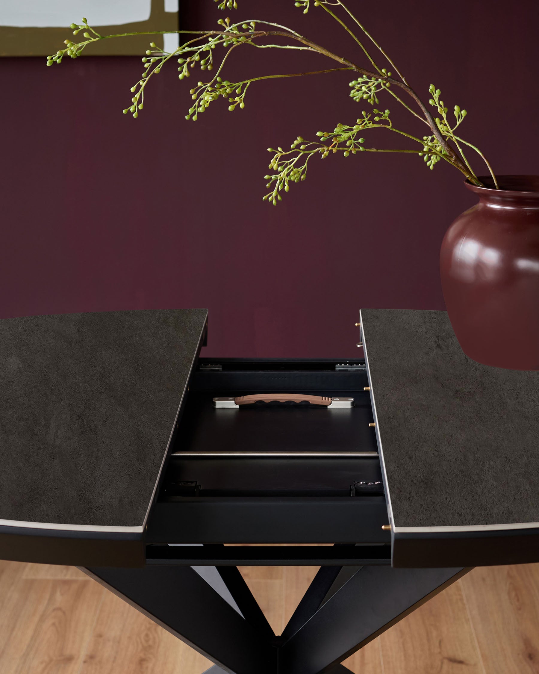 Hayden round extending dining table with dark grey ceramic top and black base, showing open drawer with wooden handle detail.