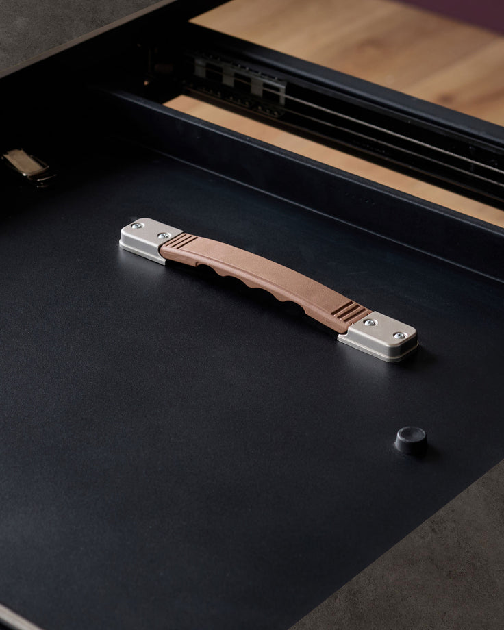 Hayden dining table handle detail: brushed nickel and natural wood pull on dark grey ceramic surface.