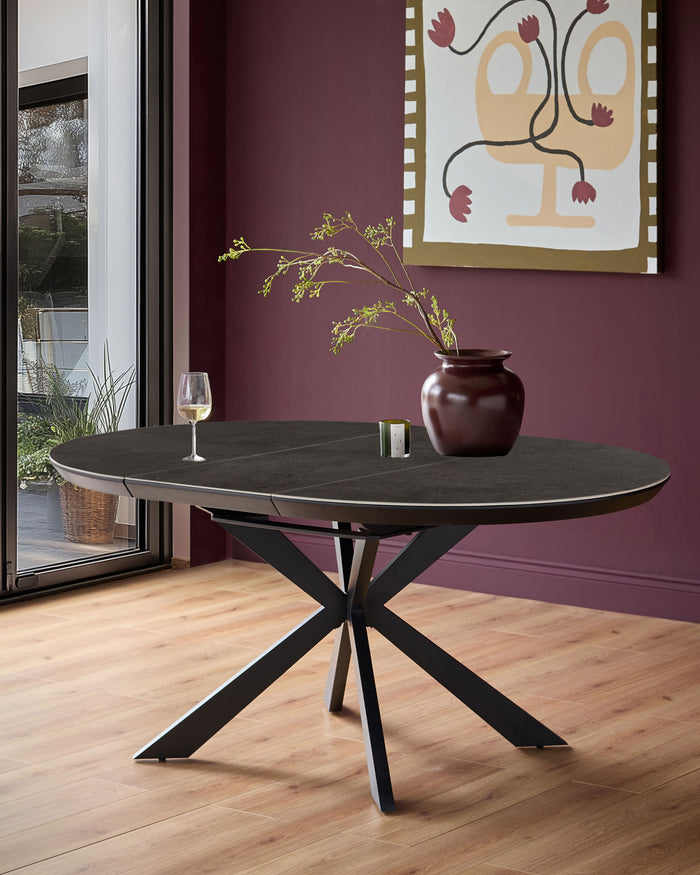 Hayden round extending dining table in dark grey ceramic with black metal X-frame base, styled in modern interior.