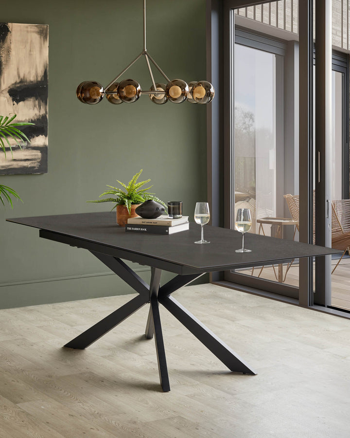 A contemporary dining table with a black base and a dark grey, extendable table top. The room has a modern, minimalist design.