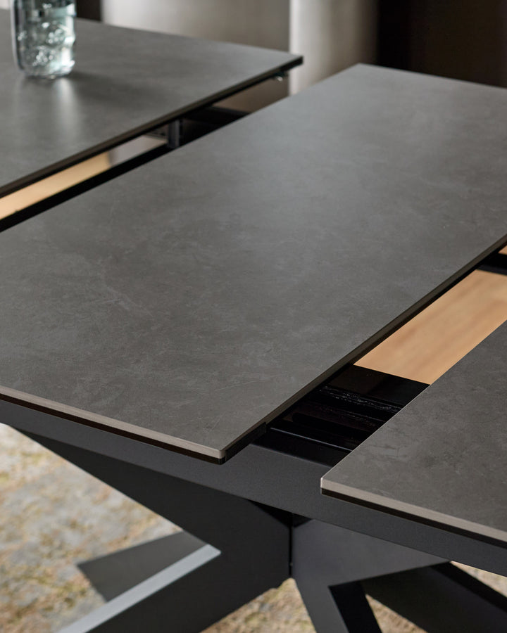 Hayden extending dining table in light grey ceramic with black frame, showing open extension leaf mechanism.