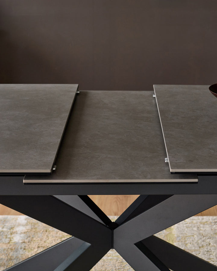 Hayden extending dining table with ceramic light grey top and black X-frame base, showing extended leaves.