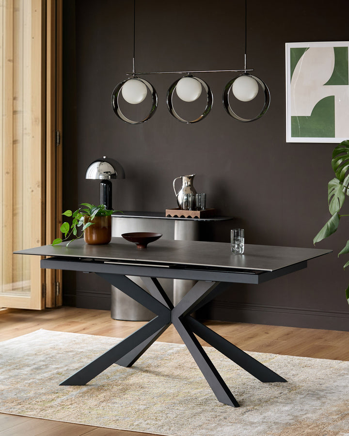 Hayden extending dining table in light grey ceramic with black metal X-frame base, shown in modern room setting.