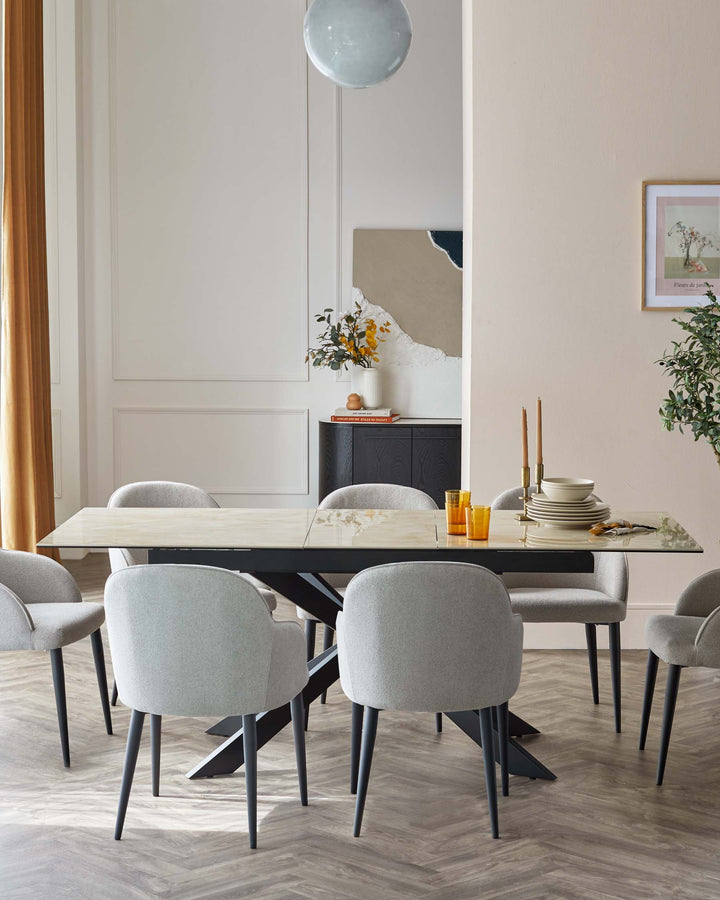 Elegant dining room featuring a rectangular table with a white marble top and contrasting black modern legs, surrounded by six grey fabric upholstered chairs with black wooden legs, all on a herringbone-patterned floor.