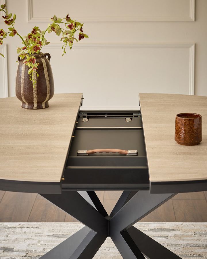 Hayden round extending dining table with natural travertine top and black X-frame base, shown with leaf extension open.