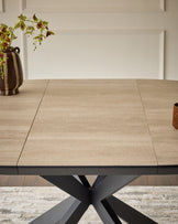 Hayden extending dining table with natural travertine ceramic top and black metal X-frame base, shown extended.