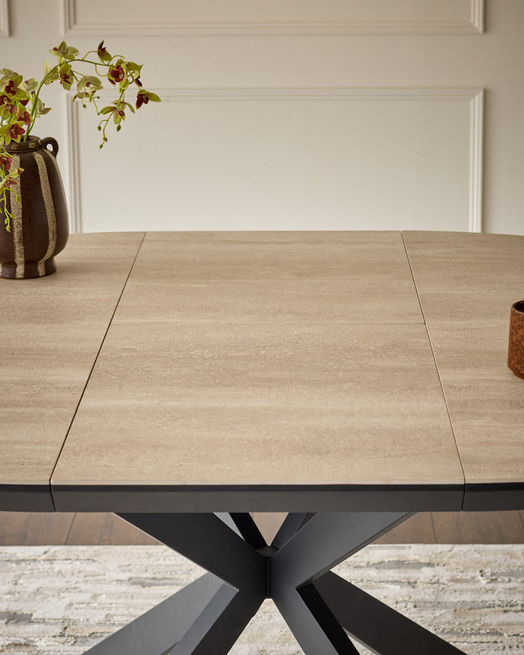 Hayden extending dining table with natural travertine ceramic top and black metal X-frame base, shown extended.