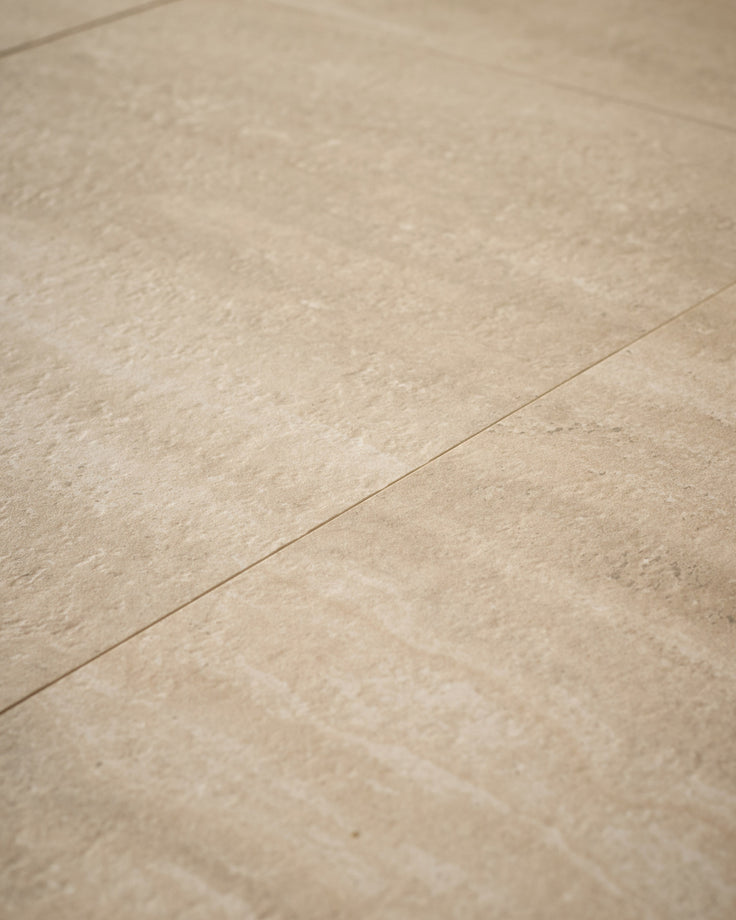 Close-up of natural travertine surface showing beige stone texture and grout line detail.