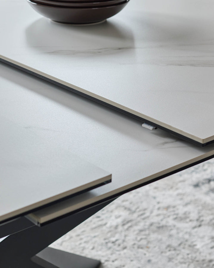 Hayden extending dining table in white ceramic, showing close-up of black metal frame and extension mechanism detail.