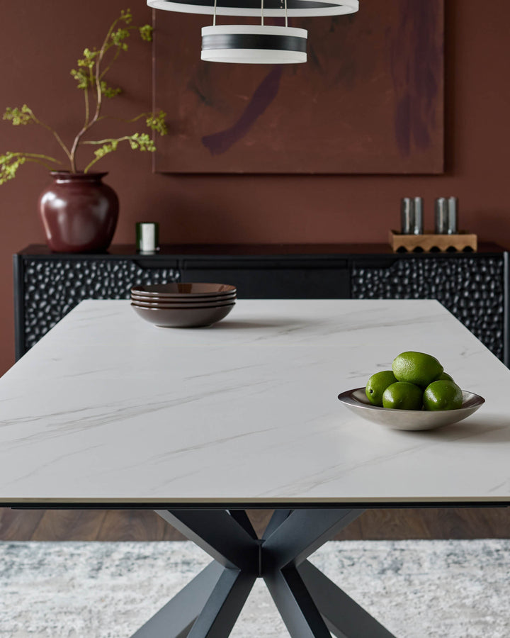 Hayden extending dining table in white ceramic with black geometric base, styled in modern dining room setting.