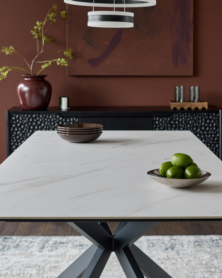 Hayden extending dining table in white ceramic with black geometric base, styled in modern dining room setting.