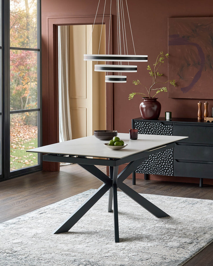 Hayden extending dining table with white ceramic top and black metal X-frame base in modern dining room setting.