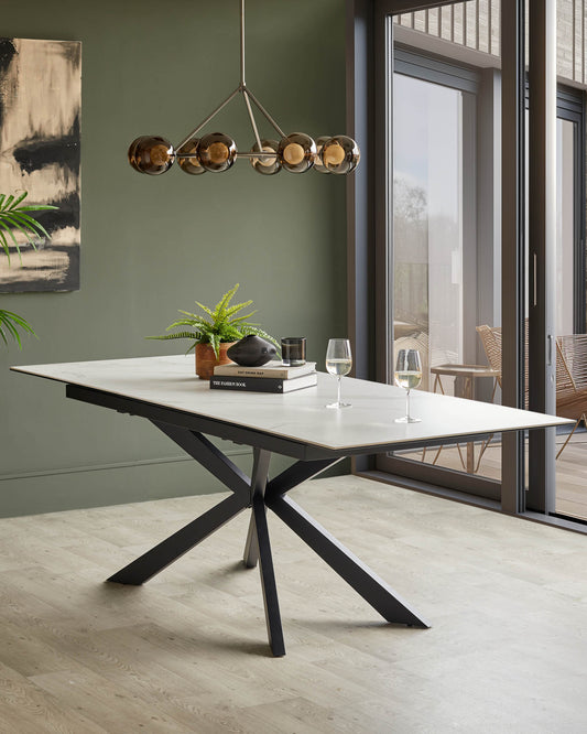 A modern dining table with a white marble effect top and dark, angular legs. There are glasses of wine on the table.