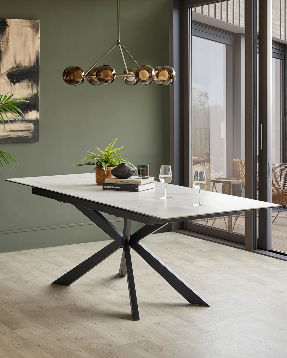 A modern dining table with a white marble effect top and dark, angular legs. There are glasses of wine on the table.