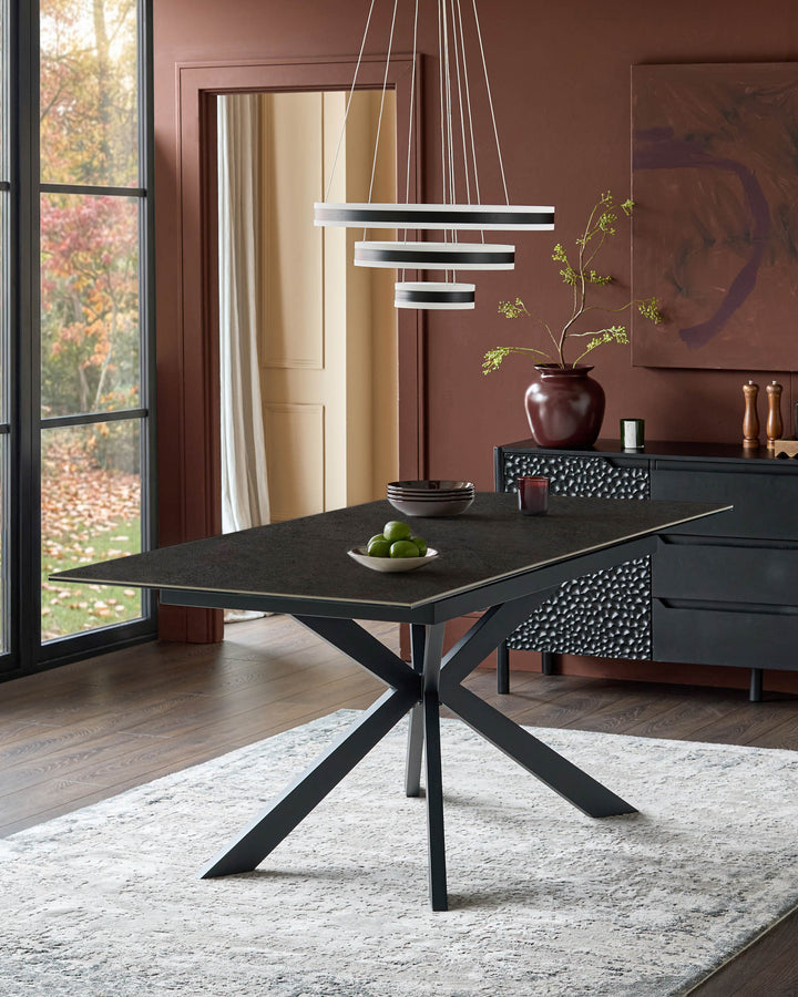 Hayden extending dining table in dark grey ceramic with black metal X-frame base, shown in modern dining room setting.