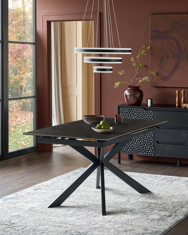 Hayden extending dining table in dark grey ceramic with black X-frame base, shown in modern dining room setting.