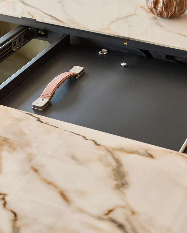 Marble-top dining table with open drawer showing leather and metal handle detail.
