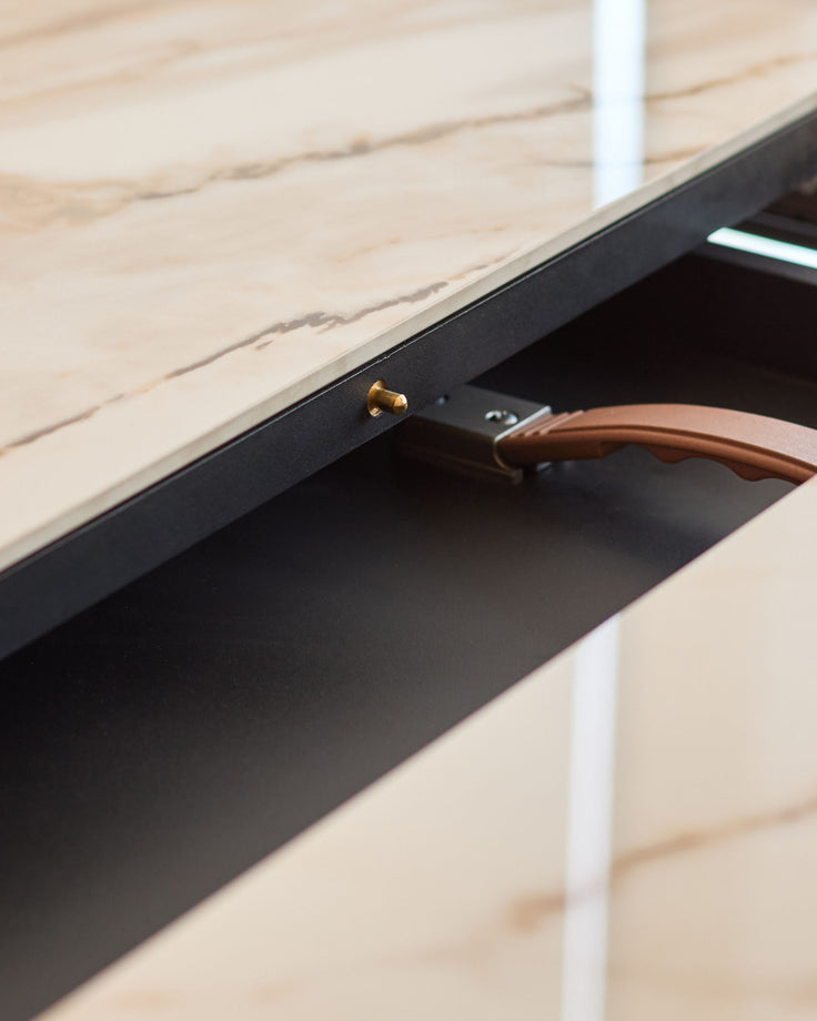Close-up of black drawer with wooden handle on natural wood dining table surface.