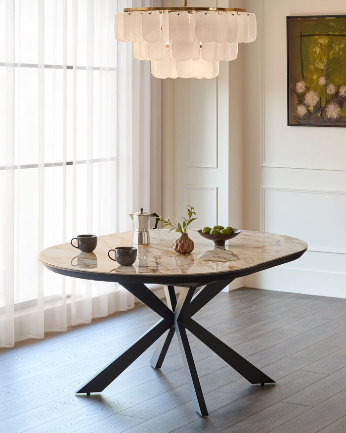 Hayden round extending dining table in natural ceramic with black X-frame base, styled in bright dining room.