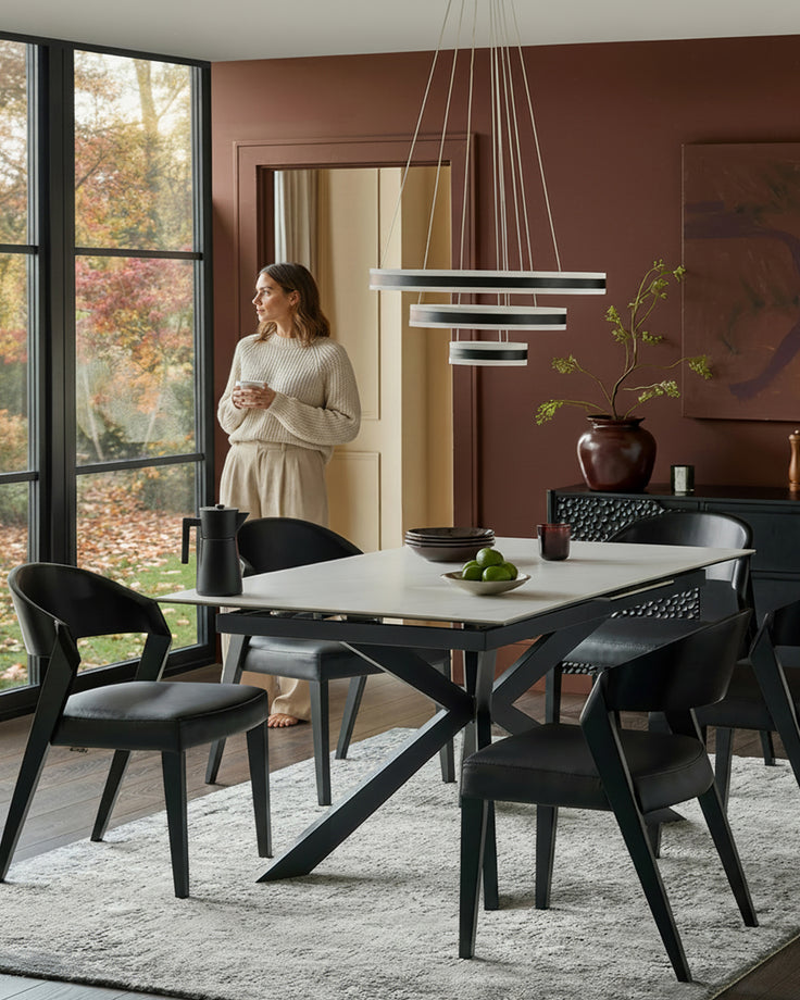 Hayden extending dining table in ceramic white with black X-frame base, styled in modern dining room setting.