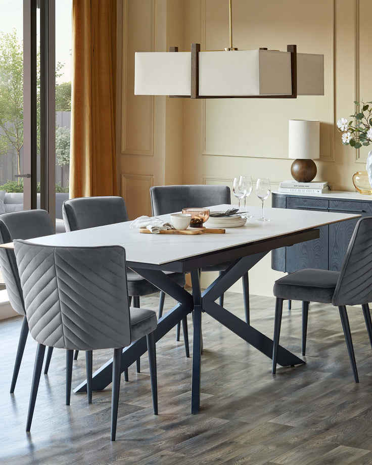 A dining set with six grey upholstered chairs, a marble-look table with a dark frame, and a matching sideboard in the background.