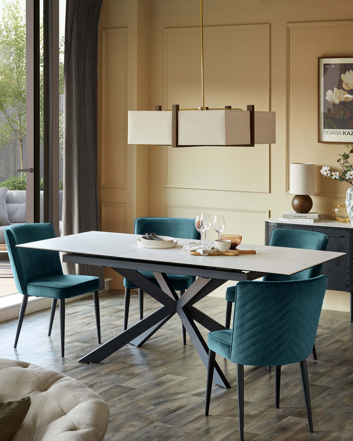 A modern dining room featuring a white table with teal chairs and a contemporary light fitting overhead.