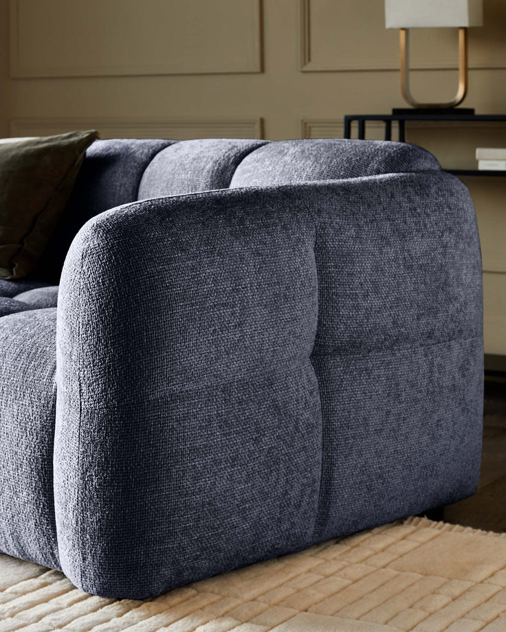 Close-up of a luxurious blue sofa with tufted cushions and a modern lamp in the background.
