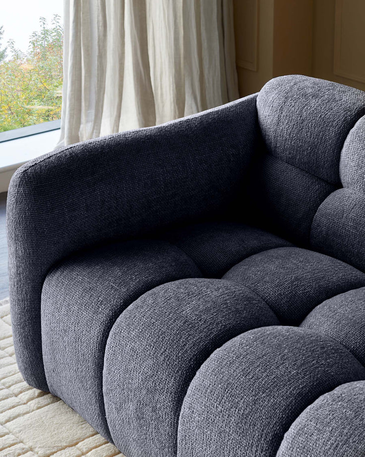 A modern, modular sofa in textured navy fabric, showcasing a cosy, inviting design with rounded sections.