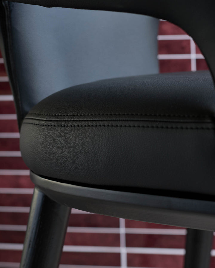 Close-up of a stylish black leather chair with a sleek frame, showcasing comfort and modern design.